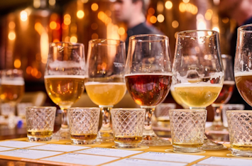 Row of beer glasses and whisky tasting glasses on a bar